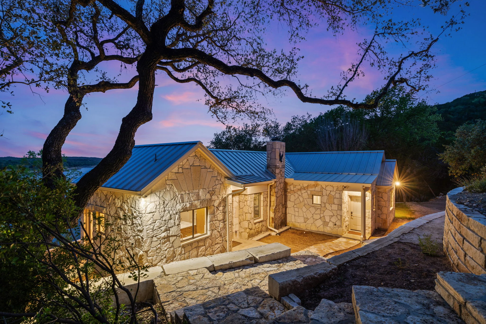 The Hearth’s restored stone exterior framed by live oak trees at twilight