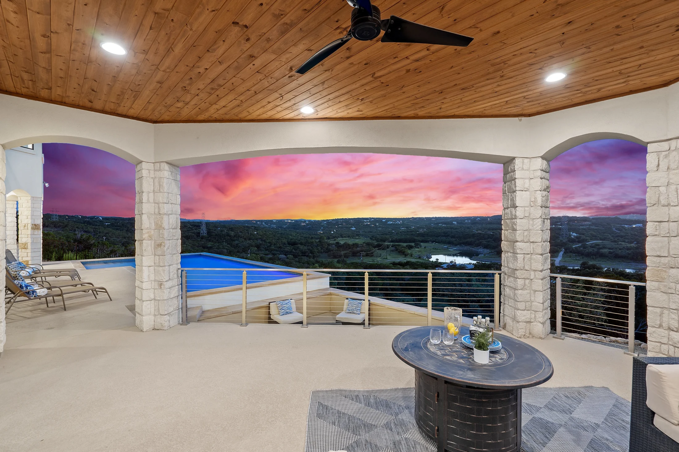 Covered outdoor living space with stone arches and sunset views