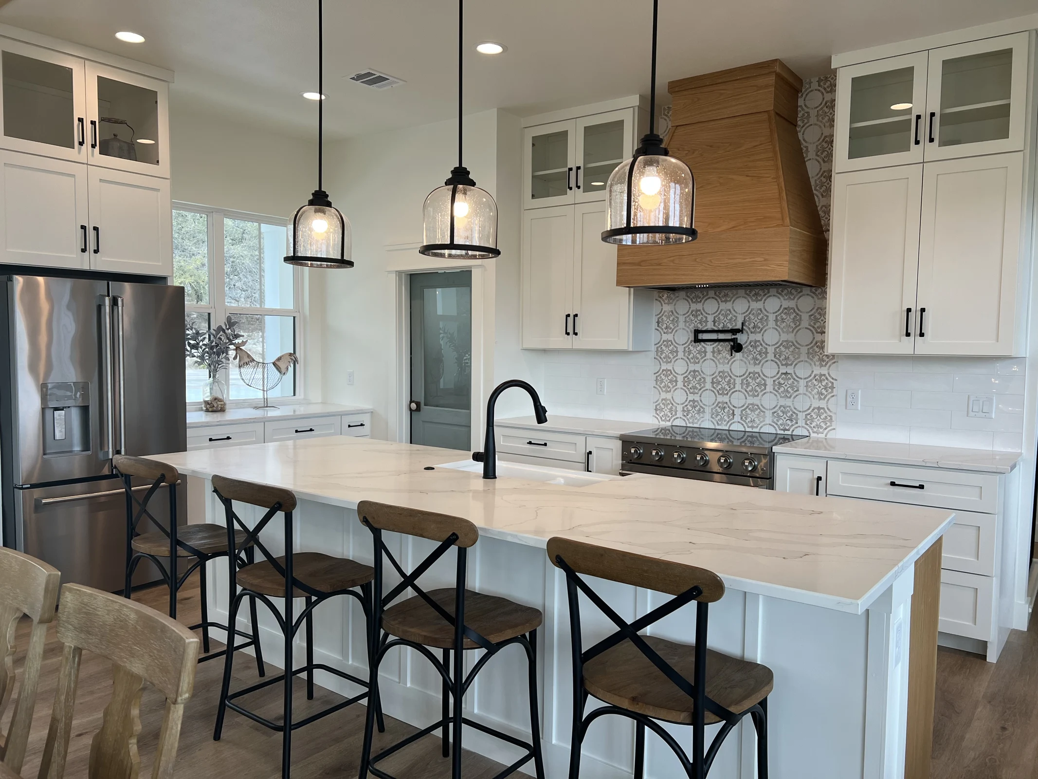 White kitchen with wood island, stone surfaces, and pendant lights